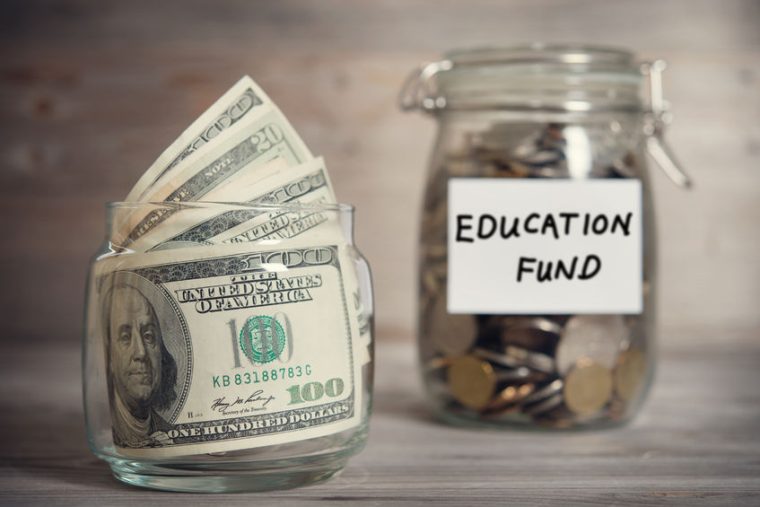 dollars and coins in glass jar with education fund label, financial concept. (Difference Scholarships Grants Loans)