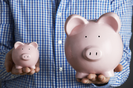 man holding large and small piggy bank concept for biggest stipends blog