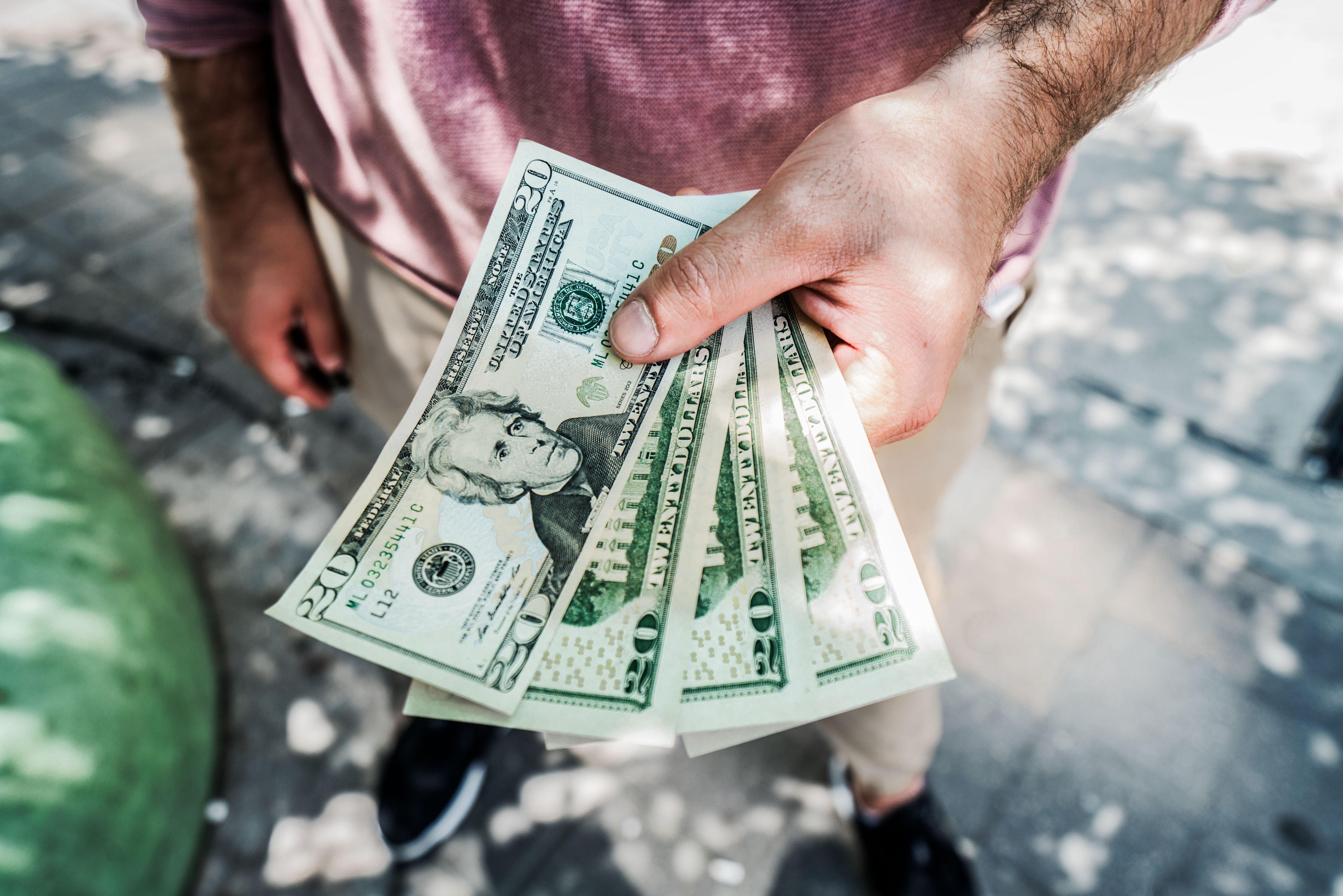 closeup of male hand holding 20 dollar bills concept for unclaimed scholarships