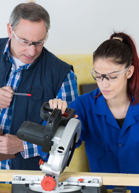 student and teacher in carpentry class using circular saw concept for technical colleges