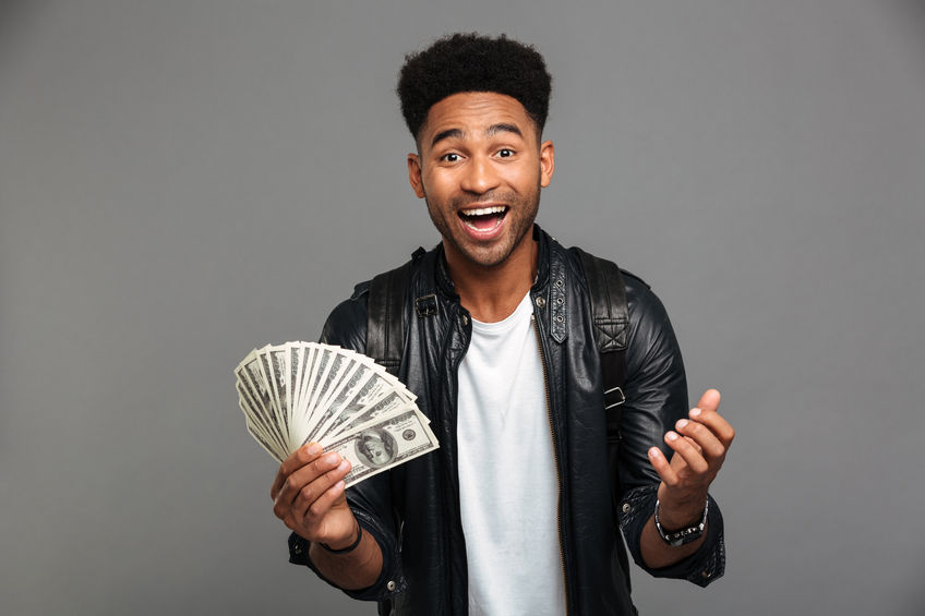 portrait of a joyful excited afro american man in leather jacket holding money banknotes concept for no-essay scholarships