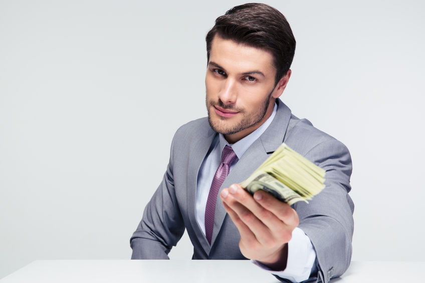 happy businessman sitting at the table and giving money on camera over gray background concept for Corporation Scholarships 