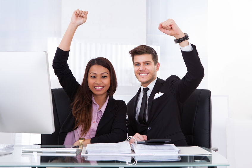Portrait of successful accountants with hands raised sitting at desk in office concept for Are Grants Taxable Income