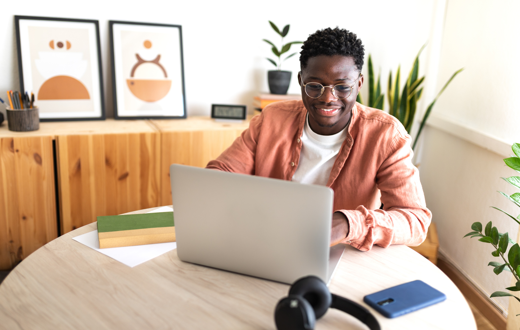 Happy black male university student studying at home using laptop.