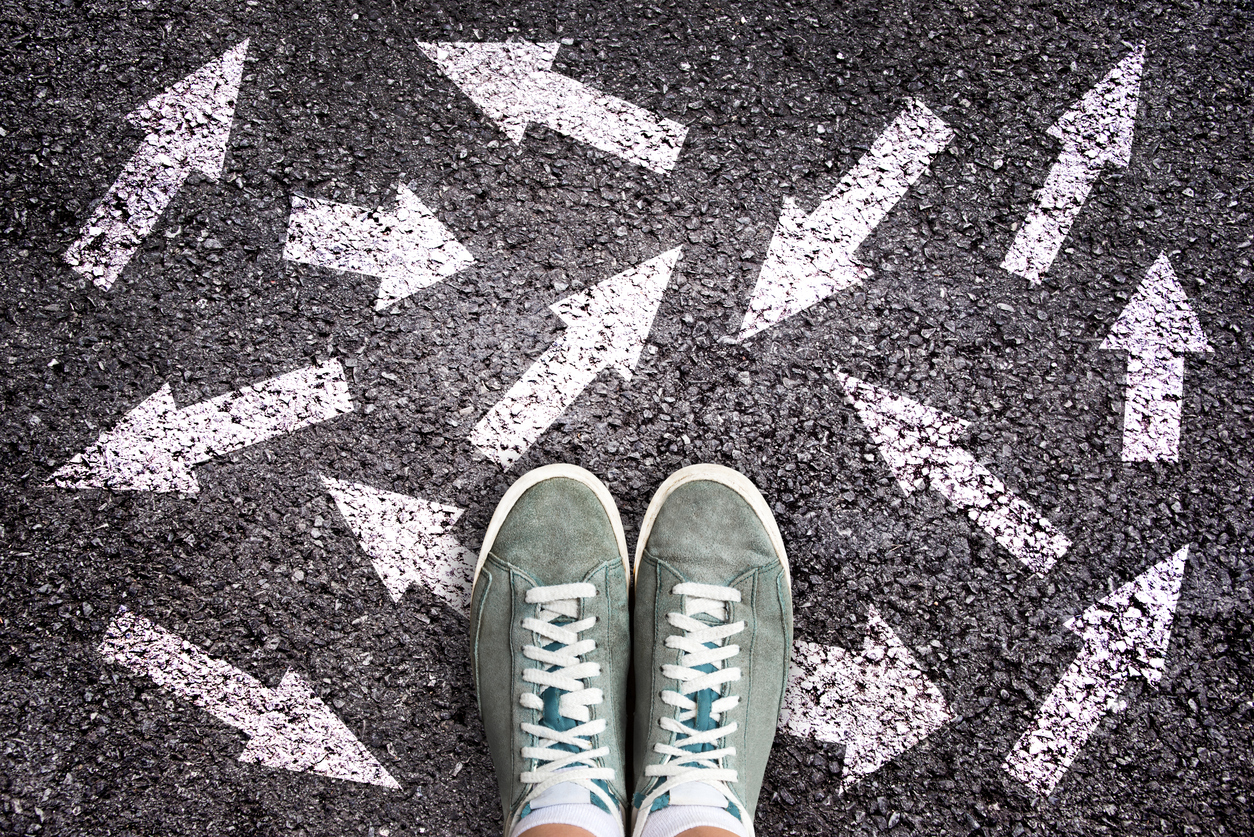 Sneaker shoes and arrows pointing in different directions on asphalt ground representing students choosing their college major