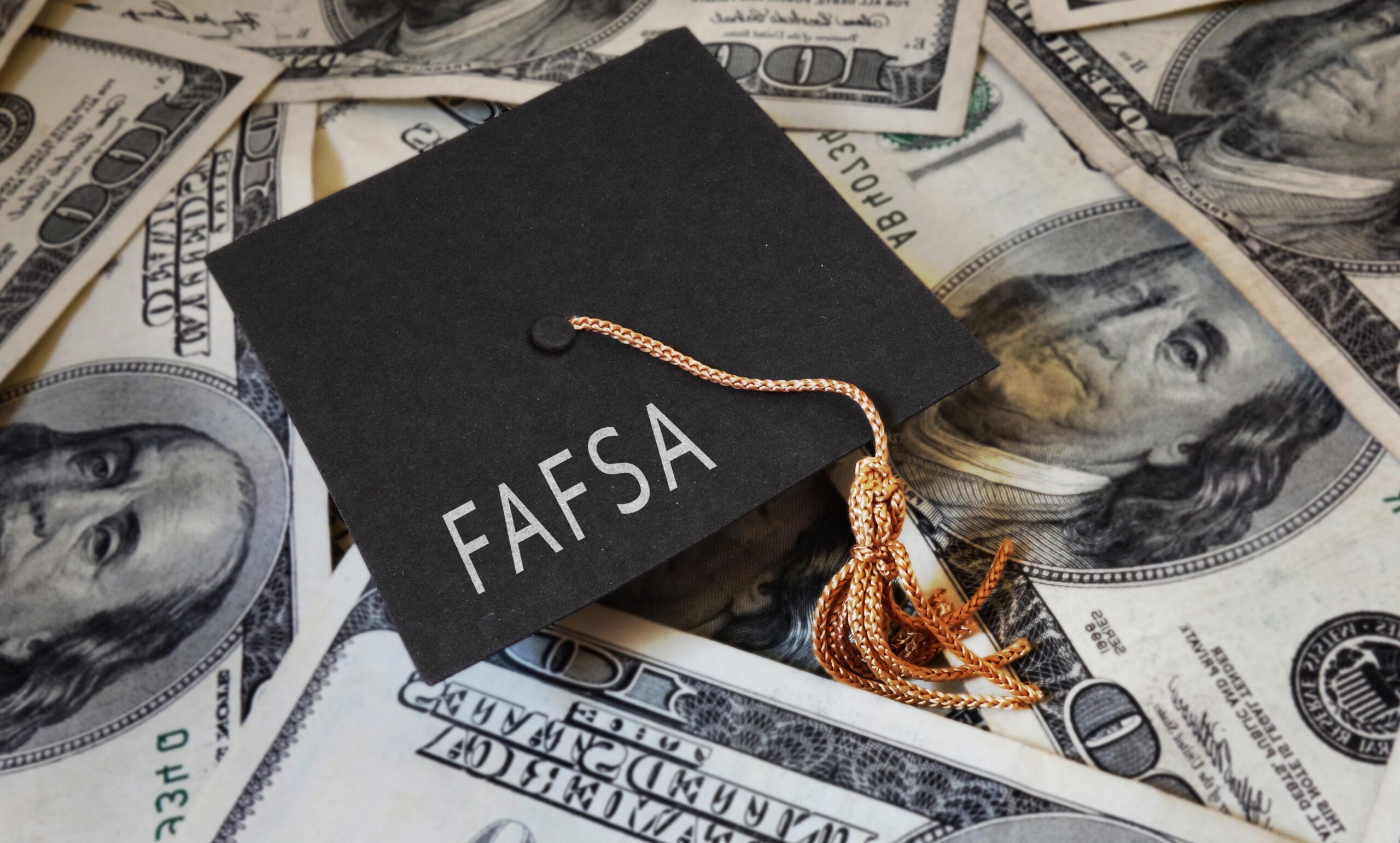 FAFSA (Free Application for Federal Student Aid) text on graduation cap and money - financial aid concept
