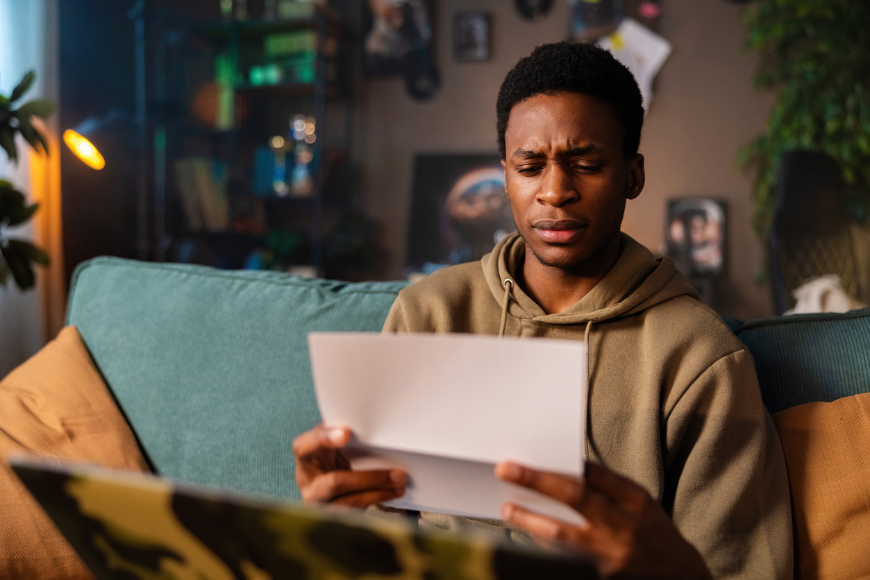 stressed young man receives wage garnishment notice about his defaulted student loan